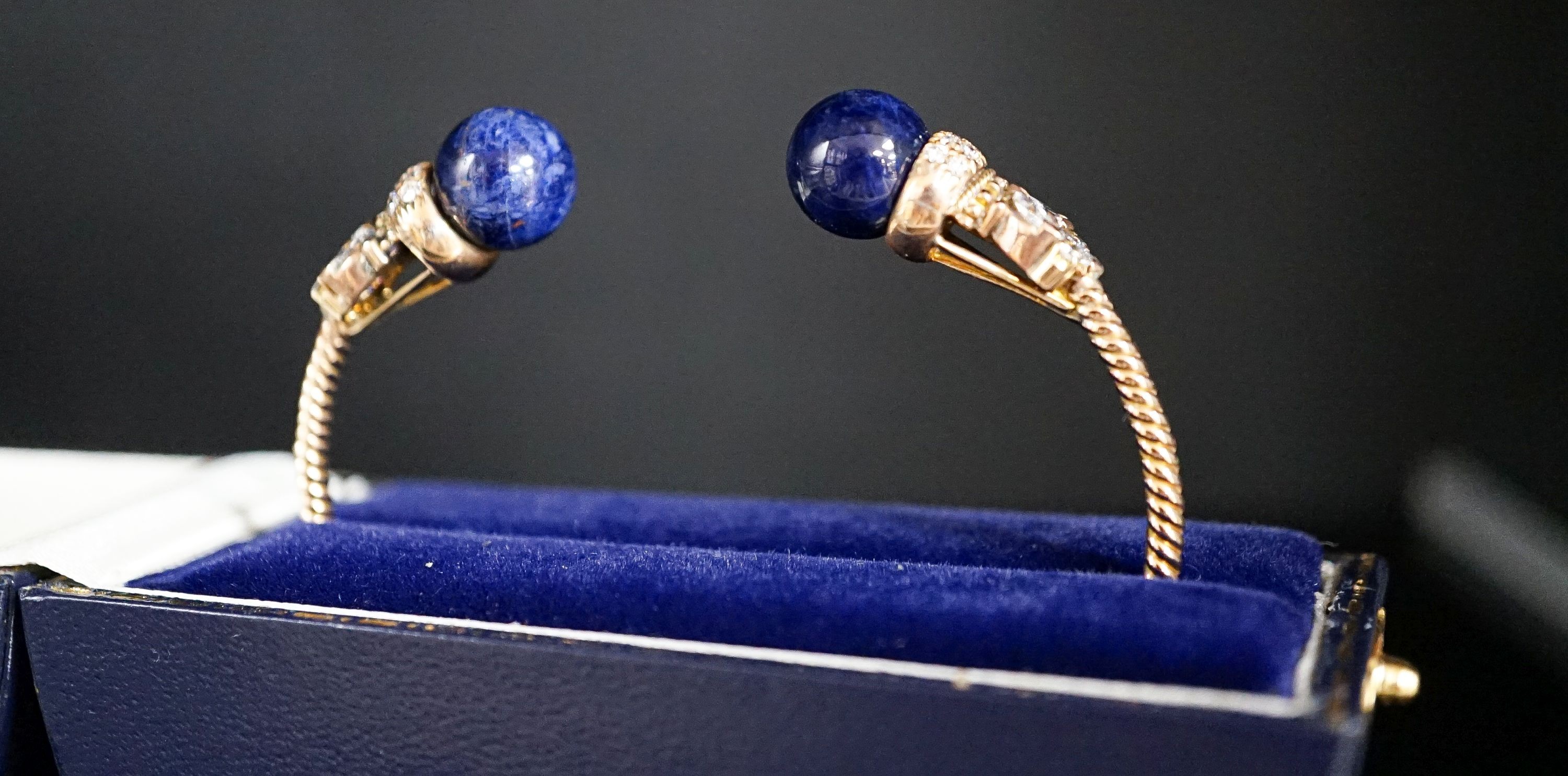 A modern yellow metal twist, two stone sodalite? and diamond set open bangle, gross weight 14 grams.